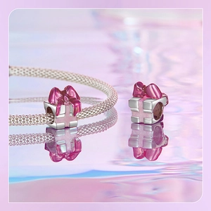 Macro view of pink enamel gift box bead charm with silver bow on snake chain