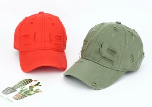 Detail of red and green distressed baseball caps with ripped edges and vintage twill texture