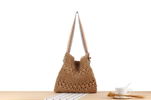 Detail of woven straw shoulder bag featuring hollow crochet flowers and a colorful strap
