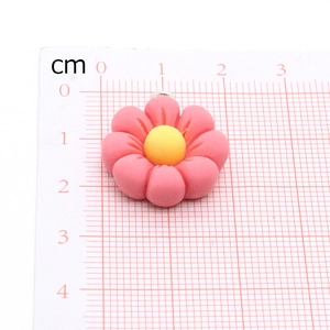 Detailed view of pink flower pendant with yellow center next to ruler showing 2cm size