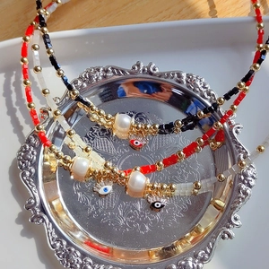 Détails des pendentifs œil maléfique et perles d'eau douce sur colliers perlés
