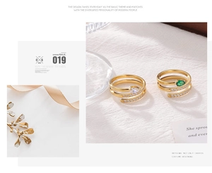 Detail of gold snake rings featuring green and white pear-cut stones with crystal accents
