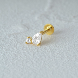 Detail of gold cartilage stud earring with drop-shaped and round clear cubic zirconia