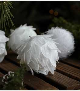Detailed view of white petal Christmas balls with glitter on festive pine branches