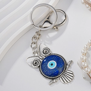 Silver metal owl keychain with blue evil eye pendant on a minimalist white background