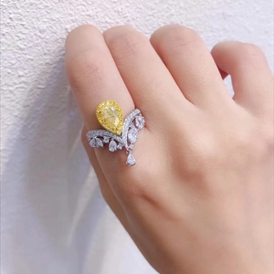 Macro detail of luxury crown ring with pear-cut yellow diamond and silver band on finger
