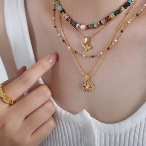 Minimalist layered necklace featuring bead pearls with gold bee and eye pendants