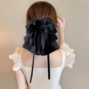 Elegant black chiffon bow hair claw with flowing ribbons shown on model's hair