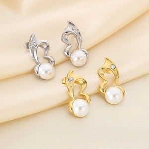 Detail of heart-shaped pearl earrings in gold and silver finish on silk fabric