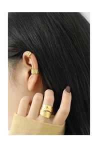 Close-up of hammered gold wide ring and minimalist layered ear cuffs on model