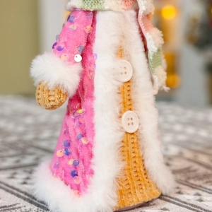 Macro detail of gingerbread doll pink sequin robe with white faux fur trim and buttons