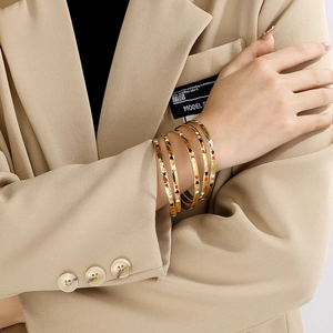 Close-up of stacked 18K gold-plated stainless steel bangles with colorful enamel hearts