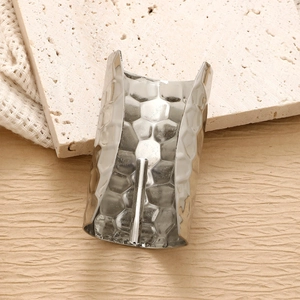 Macro shot of silver hammer-textured ponytail clip with center pin on stone surface
