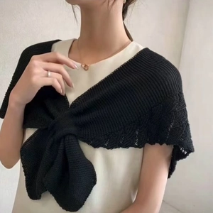 Detailed close-up of a black knitted shawl featuring a stylish decorative ribbon bow tie