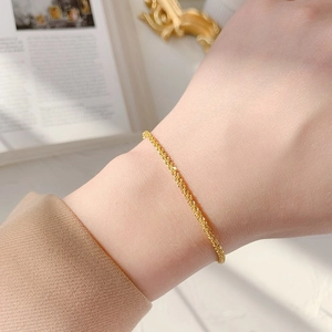 Minimalist 18K gold star tinsel chain bracelet shown elegantly on a female wrist