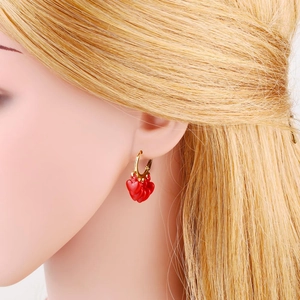 Détail de boucles d'oreilles à pampilles cœur rouge et anneau doré sur mannequin