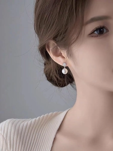 Close-up of elegant pearl drop earrings with sparkling zircon on a model's ear