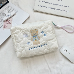 Detail of white quilted cosmetic bag with cute bear embroidery and pink zipper pull