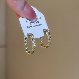 Gros plan de créoles de luxe en or avec pavé de zircons et étiquettes en argent