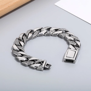 Macro shot of Cuban chain link bracelet featuring vintage Greek Key pattern engravings