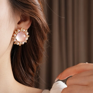 Gros plan d'une boucle d'oreille vintage tournesol avec gemme rose et perles