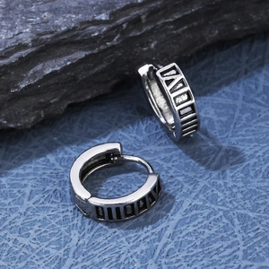Detailed macro view of vintage silver earrings with Roman numeral carvings on stone background