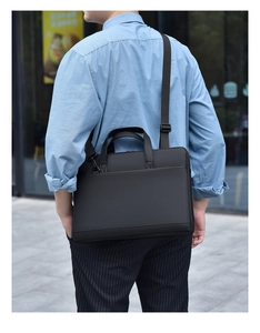 Professional slim 16 inch waterproof black laptop bag shown on a shoulder in a street setting