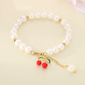Detailed view of beaded pearl bracelet featuring red cherry pendant and gold clasp