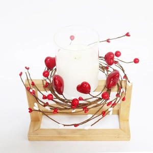 Detail of red heart berry candle ring holder in a rustic wooden tray decoration