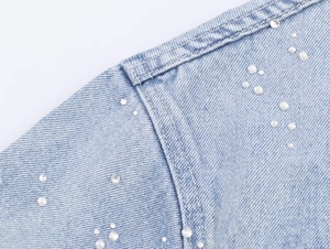 Vue détaillée du tissu denim bleu clair avec des strass étincelants et des coutures précises
