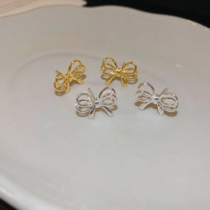 Minimalist metallic bow earrings in gold and silver finish on a ceramic tray