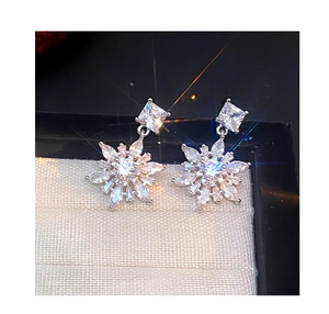 Detailed view of silver snowflake drop earrings with sparkling gems in a jewelry box