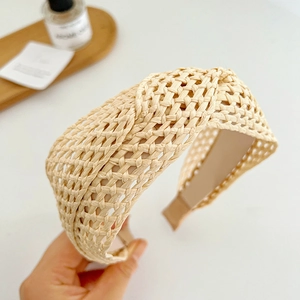 Détail d'un large serre-tête tressé beige avec un design à nœud torsadé et une texture naturelle