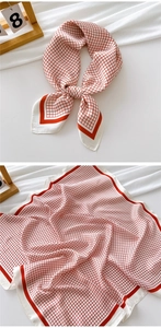 Detail view of a red and white checkered square silk scarf with smooth satin texture