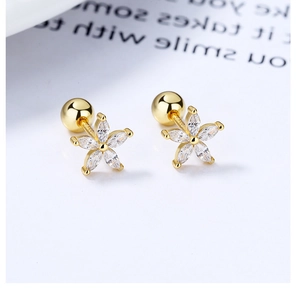 Detailed macro view of golden flower stud earrings with zircons and screw backings