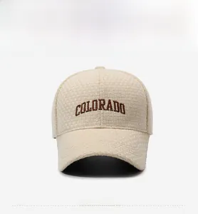 Detail of beige tweed baseball cap featuring brown COLORADO embroidery and textured fabric
