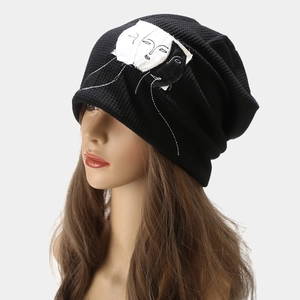 Women's black waffle knit beanie with minimalist face patch on a 45-degree side view
