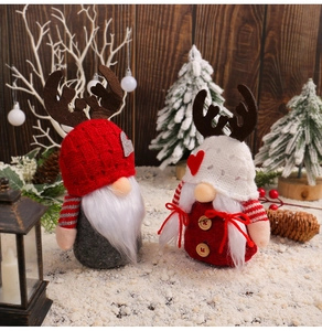 Close-up of Christmas gnome plush dolls with reindeer antlers and knitted hats on snow