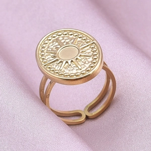 Macro detail of gold sunburst coin ring with double hollow bands on silk background