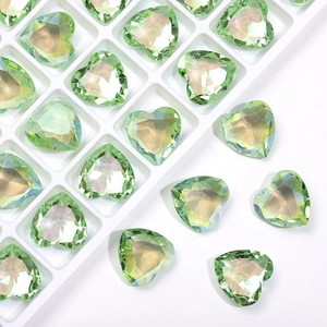 Macro detail of 12mm heart-shaped green crystal rhinestones in a white sorting tray