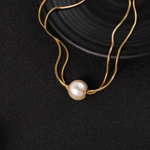 Detail of double-layered titanium necklace with gold snake chain and large pearl pendant