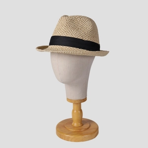 Detail of premium beige straw fedora featuring a fine weave texture and black ribbon band