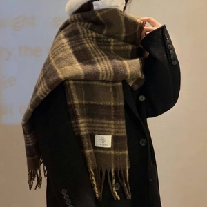Close-up of a soft brown checkered scarf with tassel details and a white woven label