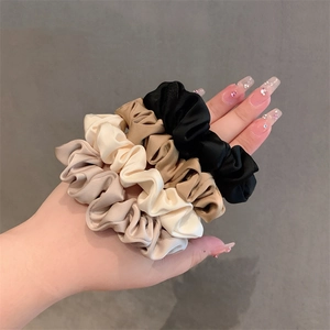Elegant satin hair scrunchies in four colors shown on wrist for versatile hairstyling