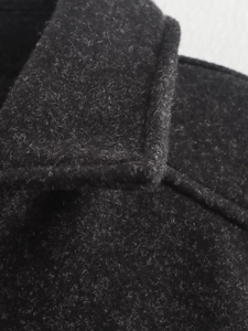 Detailaufnahme der schwarzen Tweed-Textur und präzisen Nähte der modischen Damenjacke