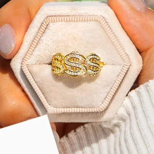 Close-up of a gold hip-hop ring with three dollar signs paved in clear zircon stones