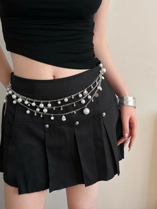 Detail of silver layered waist chain with white pearls, star and shell charms on black skirt