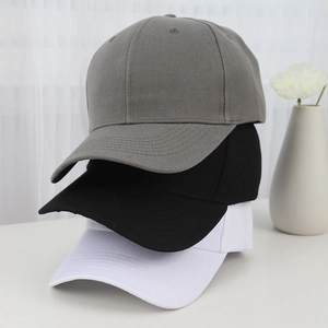Minimalist baseball caps in gray, black, and white colors stacked on a desk