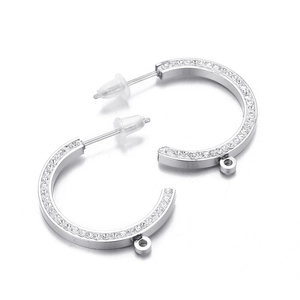Macro detail of C-shaped silver earrings with sparkling stones and small hanging loop