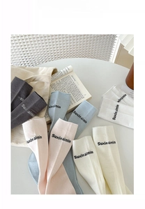 Detail view of five pairs of pastel cotton mid-calf socks with letter embroidery
